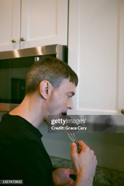 man licks chocolate mousse mix from beater - wire whisk stock pictures, royalty-free photos & images