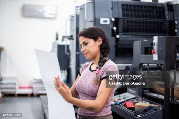 young woman working in a printing press - drukkerij stockfoto's en -beelden