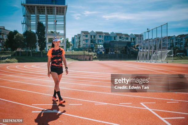 confidence satisfied female sport athlete walking at all-weather-track and field stadium in the morning - all weather running track stock pictures, royalty-free photos & images