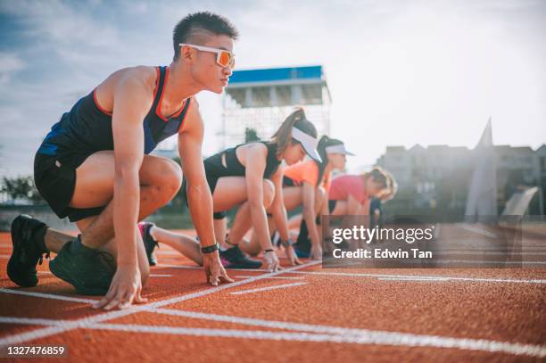 atletas chinos asiáticos haciendo fila preparándose para la línea de salida corriendo en la pista y corriendo hacia la línea de meta por la mañana en el estadio de atletismo - estadio de atletismo fotografías e imágenes de stock