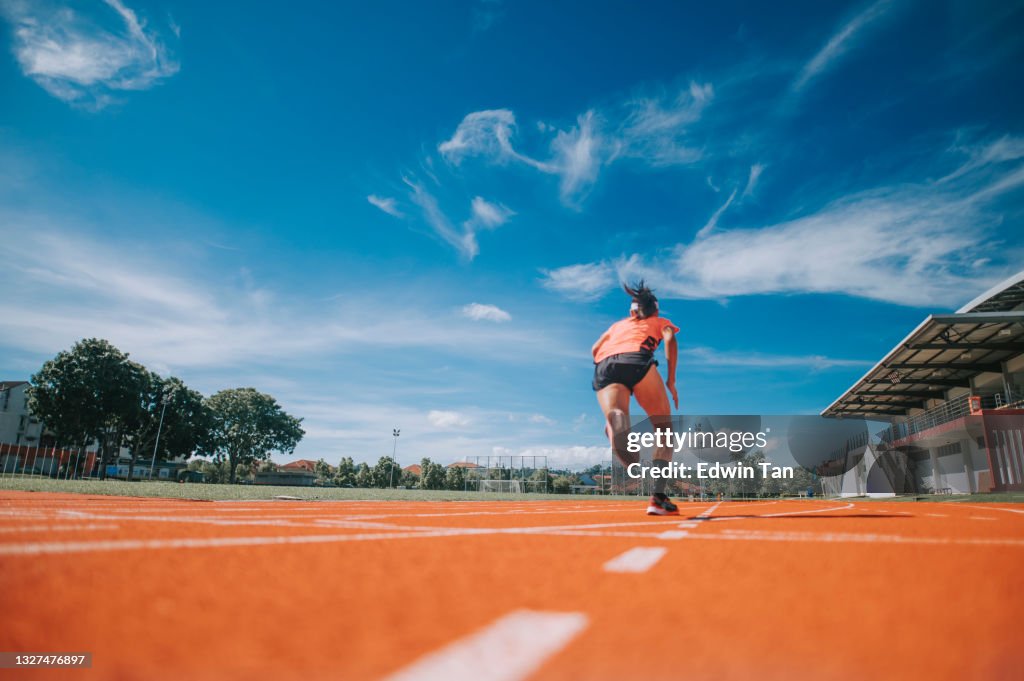 Rear view aerodynamic Asian chinese female athletes sprint running at track and run towards finishing line in the morning at track and field stadium