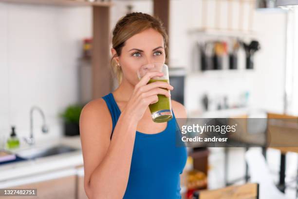 bella donna che beve un succo di disintossicazione verde - disintossicazione foto e immagini stock