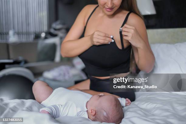 mother preparing to breastfeed her baby - bra stockfoto's en -beelden