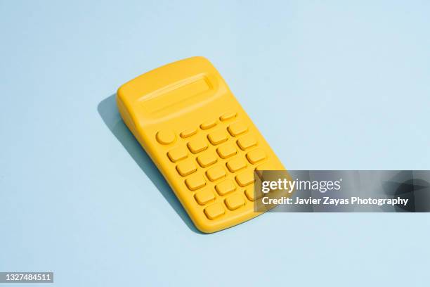 yellow calculator on blue background - calculator stockfoto's en -beelden