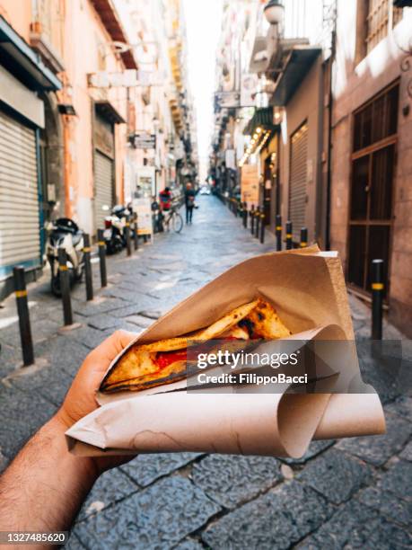 pov view of a man eating a typical "pizza a portafoglio" in naples, italy - naples italy stockfoto's en -beelden
