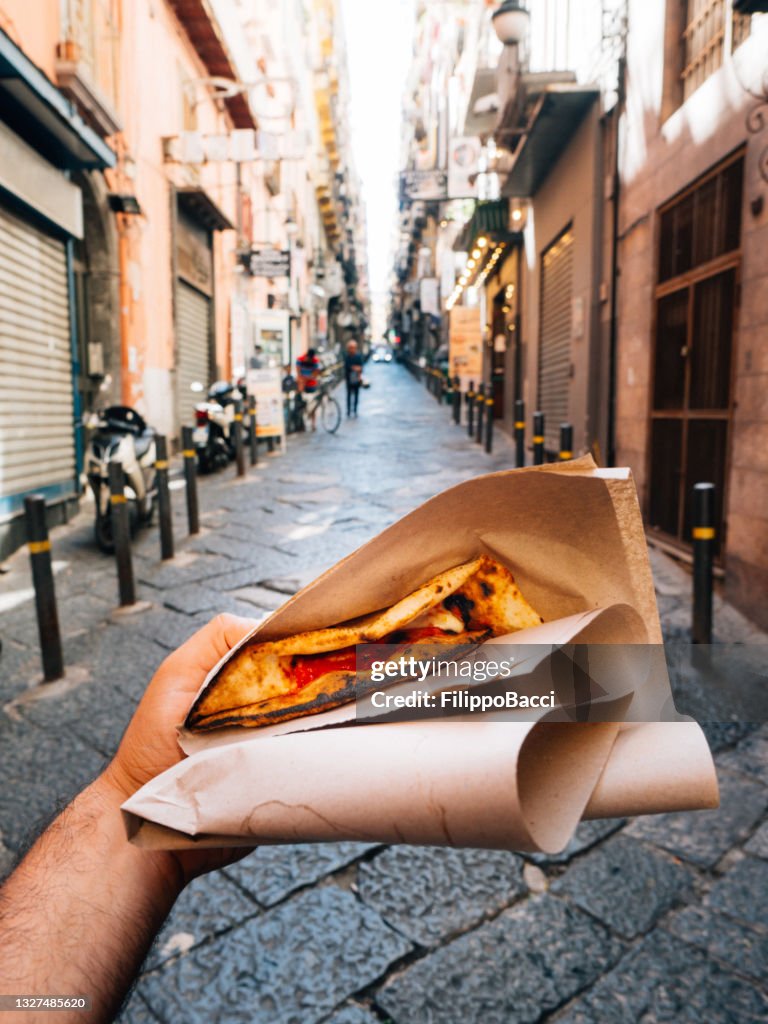 Pov view of a man eating a typical "Pizza a portafoglio" in Naples, Italy
