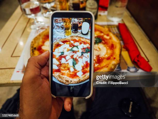 a man is taking a photo of his pizza in a restaurant in naples, italy - pizza margherita stockfoto's en -beelden