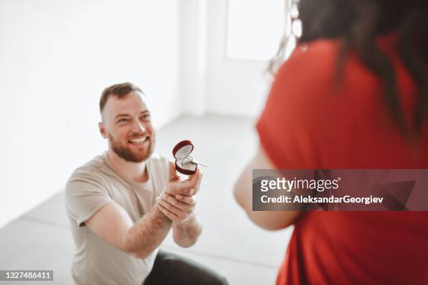 smiling bearded male kneeling to propose to girlfriend with new apartment key - engagement ring stock pictures, royalty-free photos & images