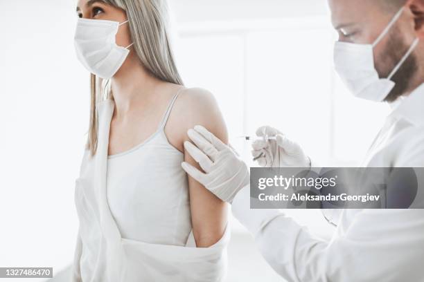 female getting first dose of covid-19 vaccine by male doctor - long term care stock pictures, royalty-free photos & images