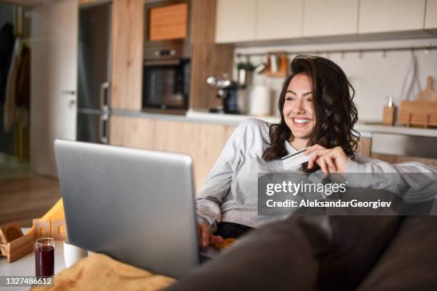 cute female smiling while drinking juice and online shopping in kitchen - sportswear shop stock pictures, royalty-free photos & images