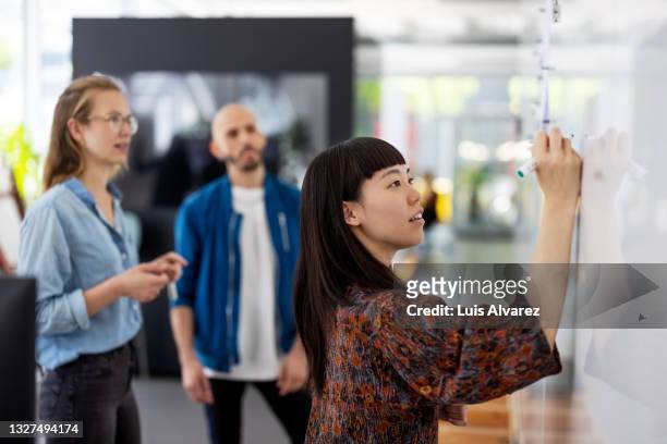 businesswoman explaining new project plan to team in office - woman whiteboard fotografías e imágenes de stock