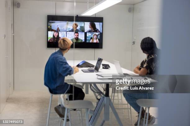 business people sitting inside conference room having a video call - remote location stock-fotos und bilder