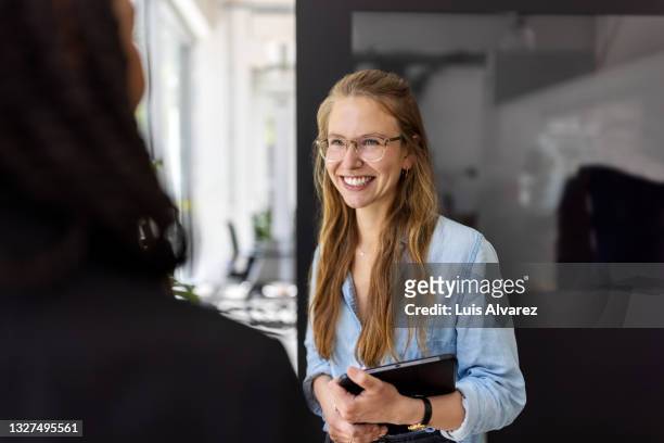 woman talking with colleague and smiling in office - agile business stockfoto's en -beelden