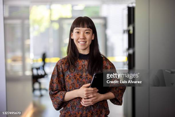 asian businesswoman standing in hybrid office - neu stock-fotos und bilder