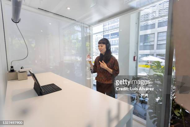 businesswoman having video call meeting inside her cubicle - cubicle photos et images de collection