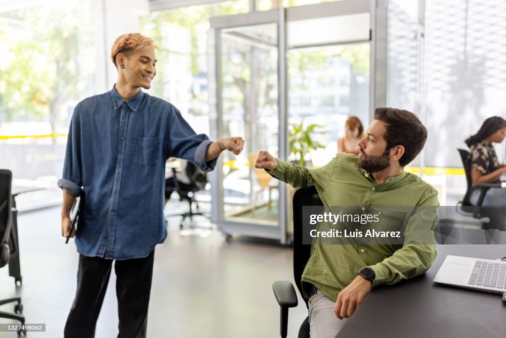 Office colleagues greeting each other with fist bump