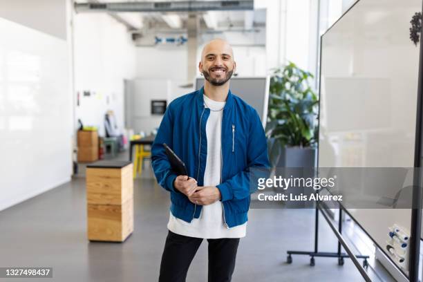 portrait of a bald businessman holding digital tablet - portretfoto stockfoto's en -beelden