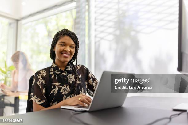 smiling young woman sitting office desk - intern foto e immagini stock