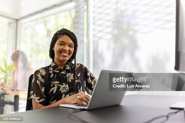 smiling young woman sitting office desk - woman business desk front laptop office bildbanksfoton och bilder