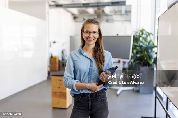 portrait of a businesswoman with digital tablet in office - business woman standing office stock-fotos und bilder