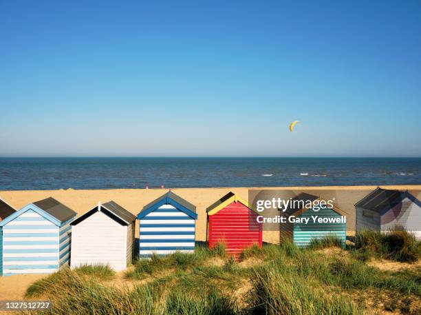 multi coloured beach huts against blue sky - suffolk beach stock pictures, royalty-free photos & images