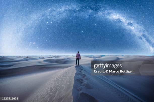 man hiking in the desert at night under the milky way - majestoso - fotografias e filmes do acervo