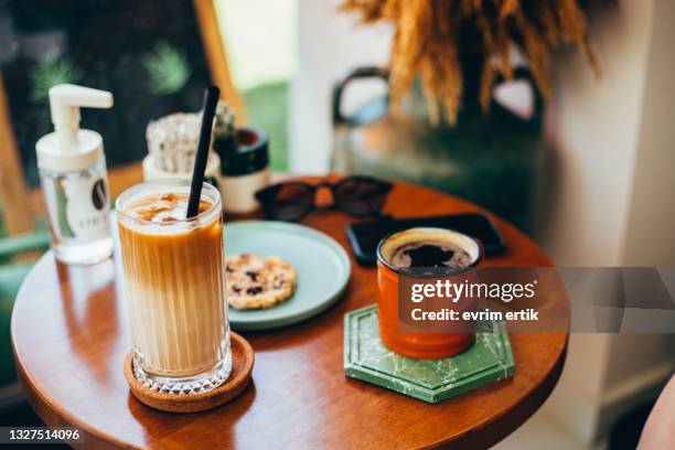 ice latte americano and a cookie on the coffee table - kaki stockfoto's en -beelden