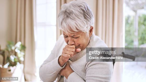 schuss einer seniorin, die hustet, während sie zu hause im rollstuhl sitzt - woman cough stock-fotos und bilder