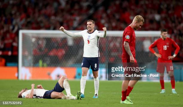 Harry Kane and Jordan Henderson of England celebrate following their team's victory as Simon Kjaer of Denmark looks dejected following his team's...