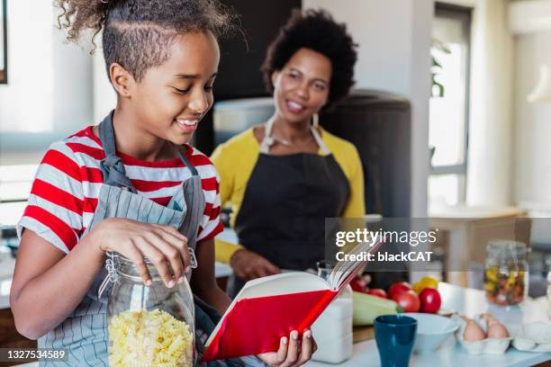 mother and daughter have fun in the kitchen and make a meal - cookbook stock pictures, royalty-free photos & images