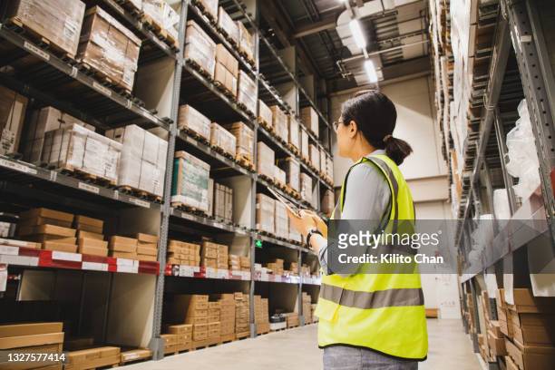 asian businesswoman holding a digital tablet working at a warehouse - warehouse inventory stock pictures, royalty-free photos & images