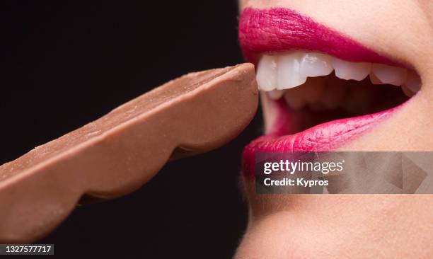 woman's hand holding piece of chocolate - candy lips stock pictures, royalty-free photos & images