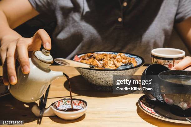 asian woman enjoying japanese food and pouring soy sauce to a saucer - soy sauce stock pictures, royalty-free photos & images