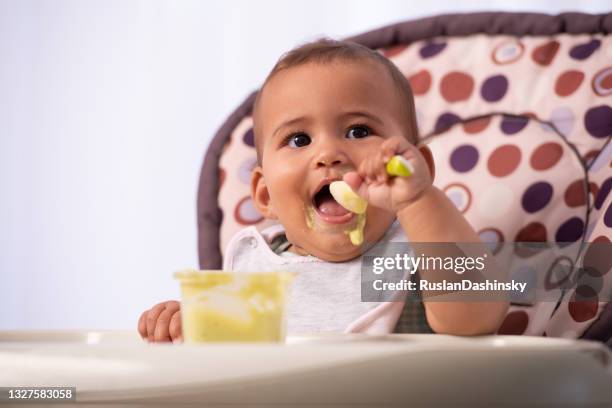 adorable baby eating food by himself. - baby food spill stock pictures, royalty-free photos & images