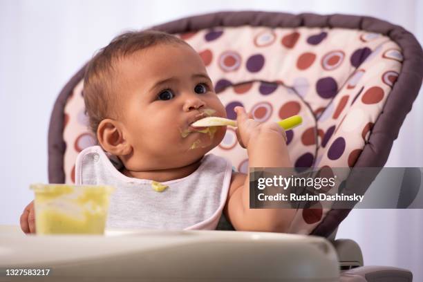 adorable baby eating food by himself. - baby food spill stock pictures, royalty-free photos & images