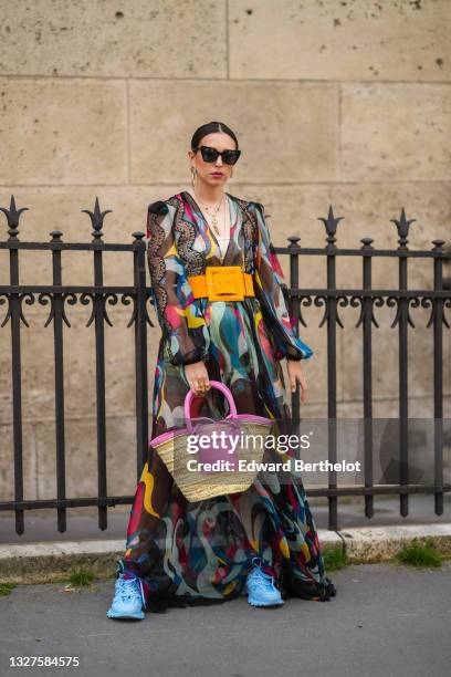 Gabriella Berdugo wears black sunglasses, silver and gold earrings, silver and gold chain pendant necklaces, a beige ribbed headband t-shirt, a black...