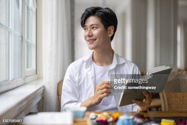 homem asiático lendo em uma cafeteria - handsome asian guy - fotografias e filmes do acervo