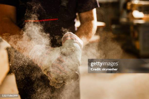 close up of unrecognizable worker cleaning dust from his gloves. - wood sawdust stock pictures, royalty-free photos & images