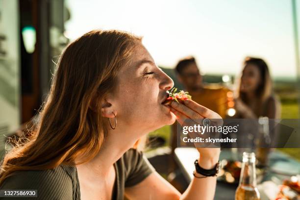 happy woman enjoying in sandwich during camping with her friends. - bijten stockfoto's en -beelden