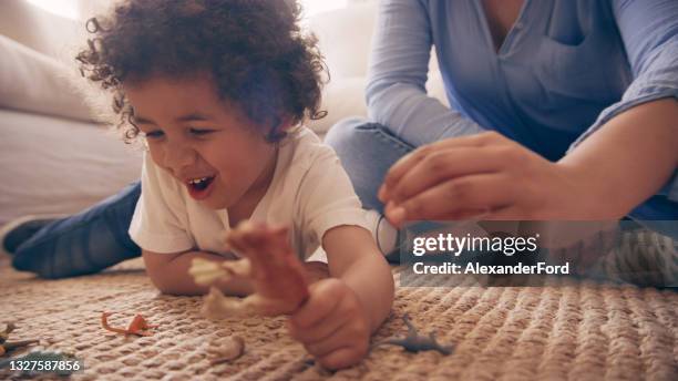 shot of a little boy and his mother playing with toy dinosaurs together at home - child playing with toys stock pictures, royalty-free photos & images