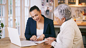 Shot of a consultant going through paperwork during a meeting with a senior woman at home