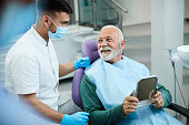 Satisfied senior man communicating with his dentist after dental procedure at dentist's office.
