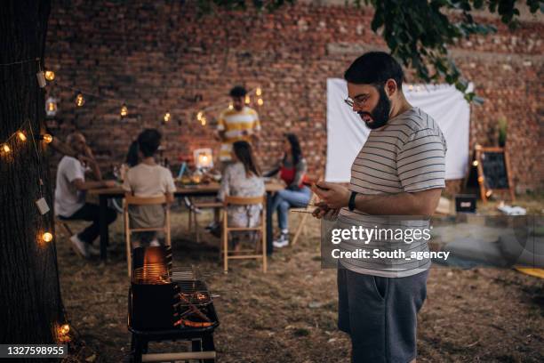 man making barbecue for friends - large dinner party stock pictures, royalty-free photos & images
