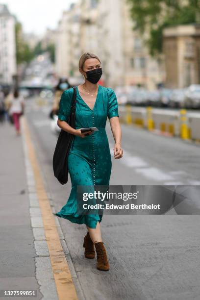 Guest wears gold earrings, a green shiny pattern puffy short sleeves and buttoned V-neck flowing long dress, a black leather large shoulder bag, a...