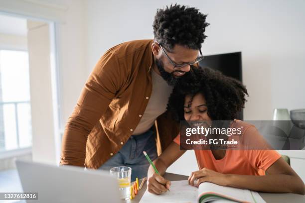padre ayudando a la hija con la tarea - parents fotografías e imágenes de stock