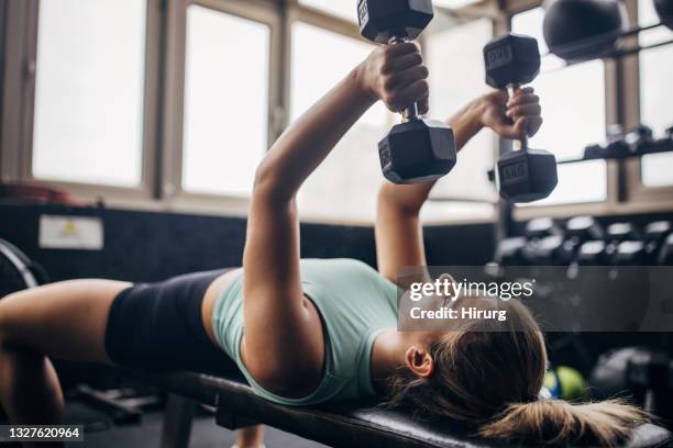 young woman training with dumbbells - women's weightlifting stock pictures, royalty-free photos & images