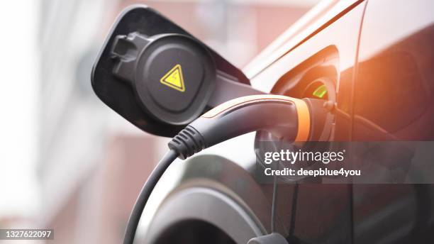 veículo slectric está estacionado na rua e está sendo carregado - posto de carregamento de veículos elétricos - fotografias e filmes do acervo
