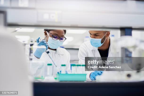 shot of two young scientists conducting medical research in a laboratory - two shot stock pictures, royalty-free photos & images