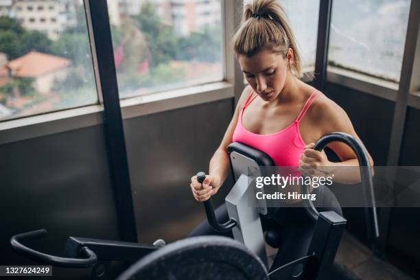 fit woman training on exercise machine - women's weightlifting stock pictures, royalty-free photos & images