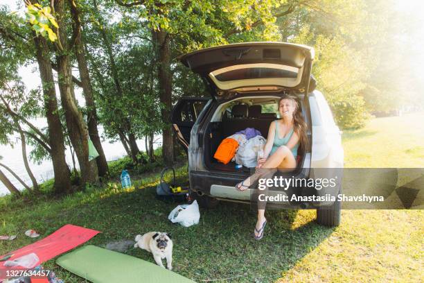 young happy woman having the best summer time outdoors camping by the lake with a dog - extreem weer stock pictures, royalty-free photos & images